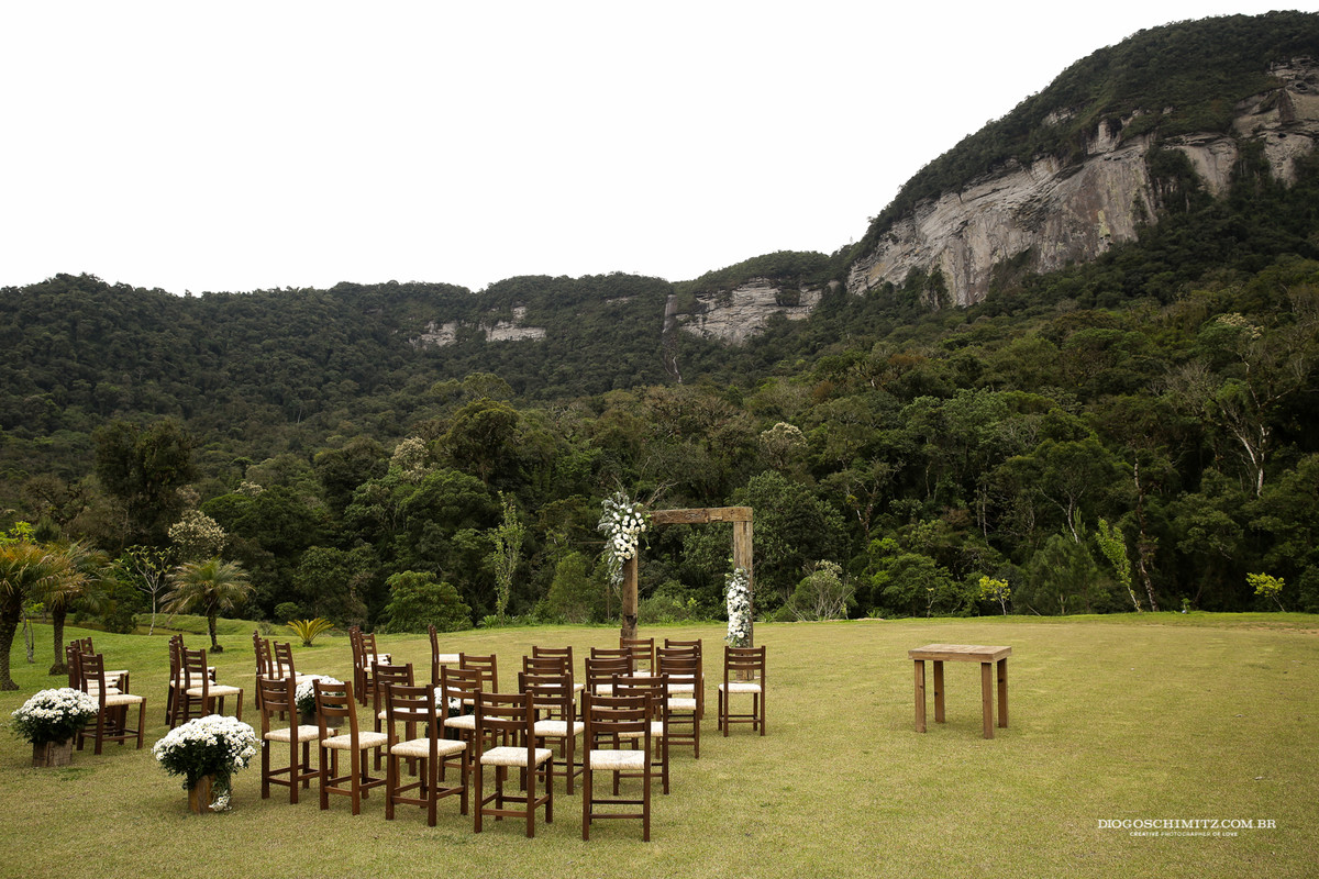 Decoração de casamento ao ar livre, cadeiras e arco com flores.