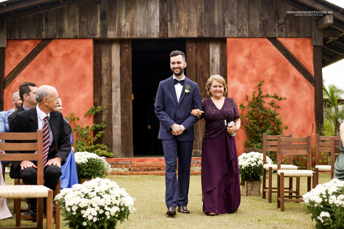 Noivo entrando na cerimônia no campo com sua mãe.