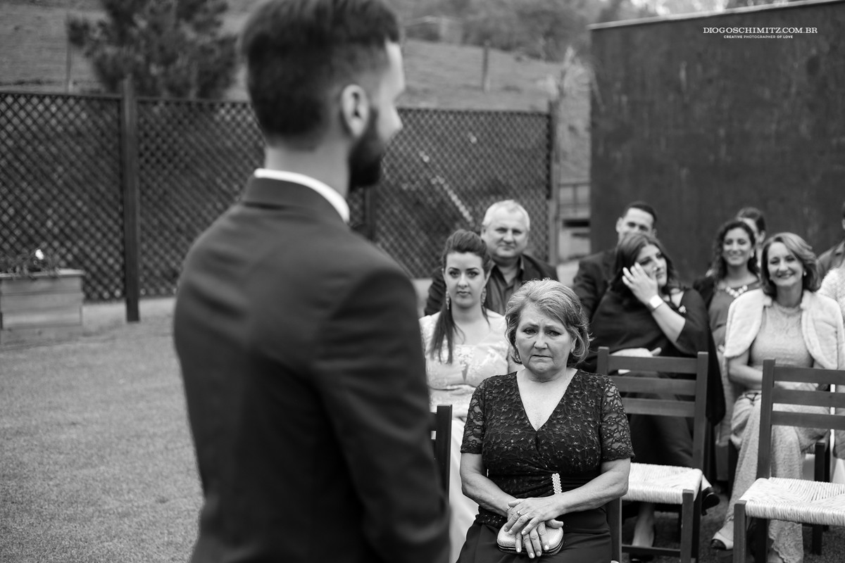 Reação da mãe do noivo ao ver seu filho na cerimônia de casamento no campo.