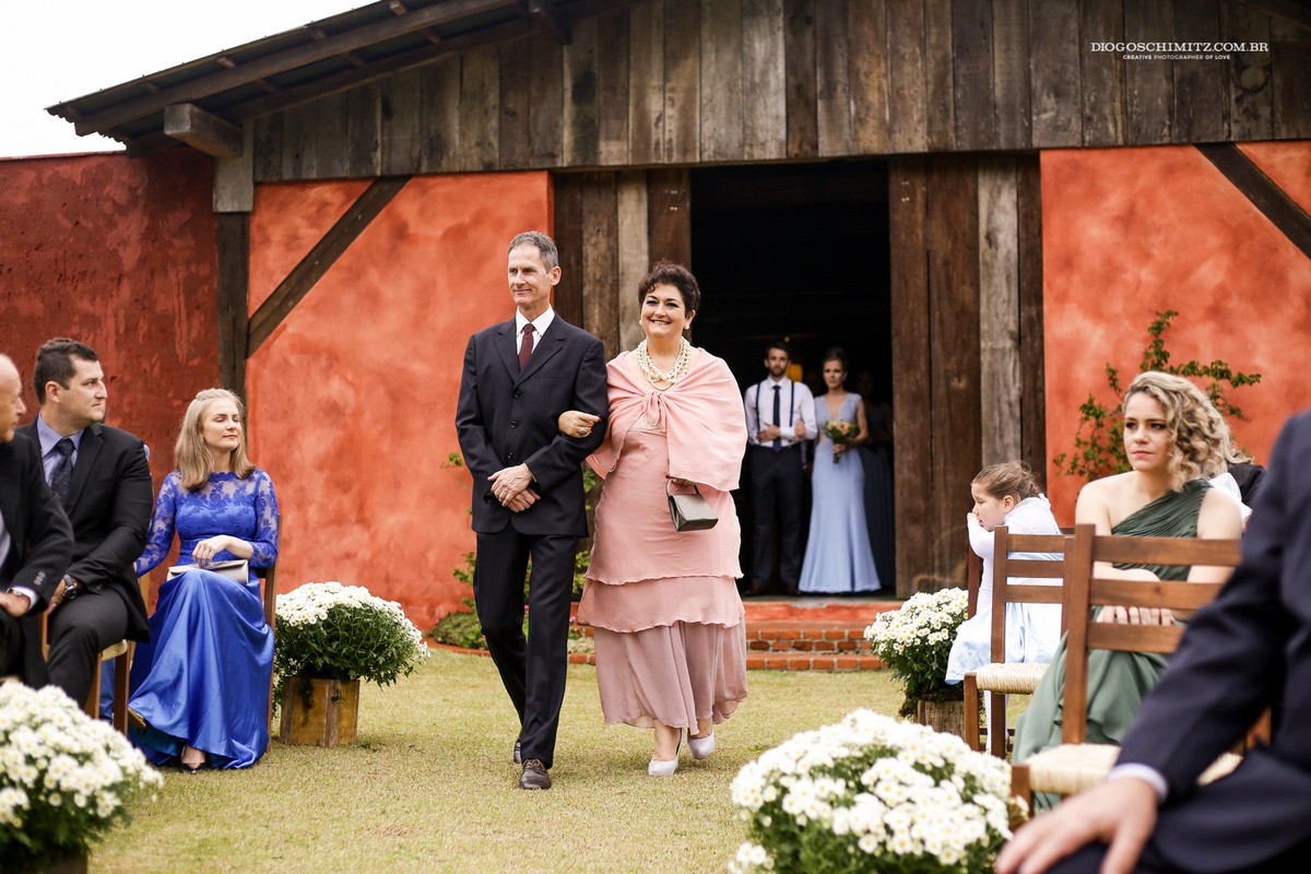 Casal de padrinhos entrando na cerimônia do casamento no campo.