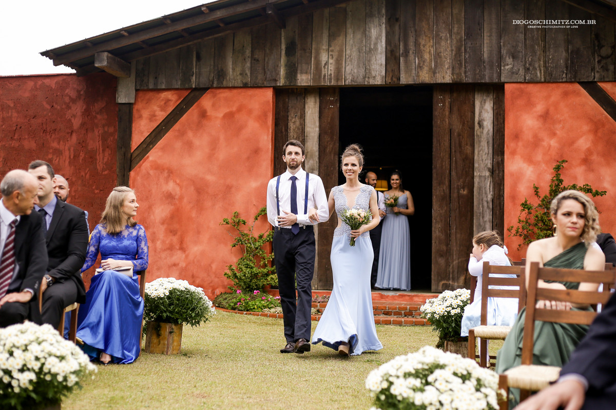 Casal de padrinhos entrando na crimônia do casamento no campo, vestido de madrinha com buquê.