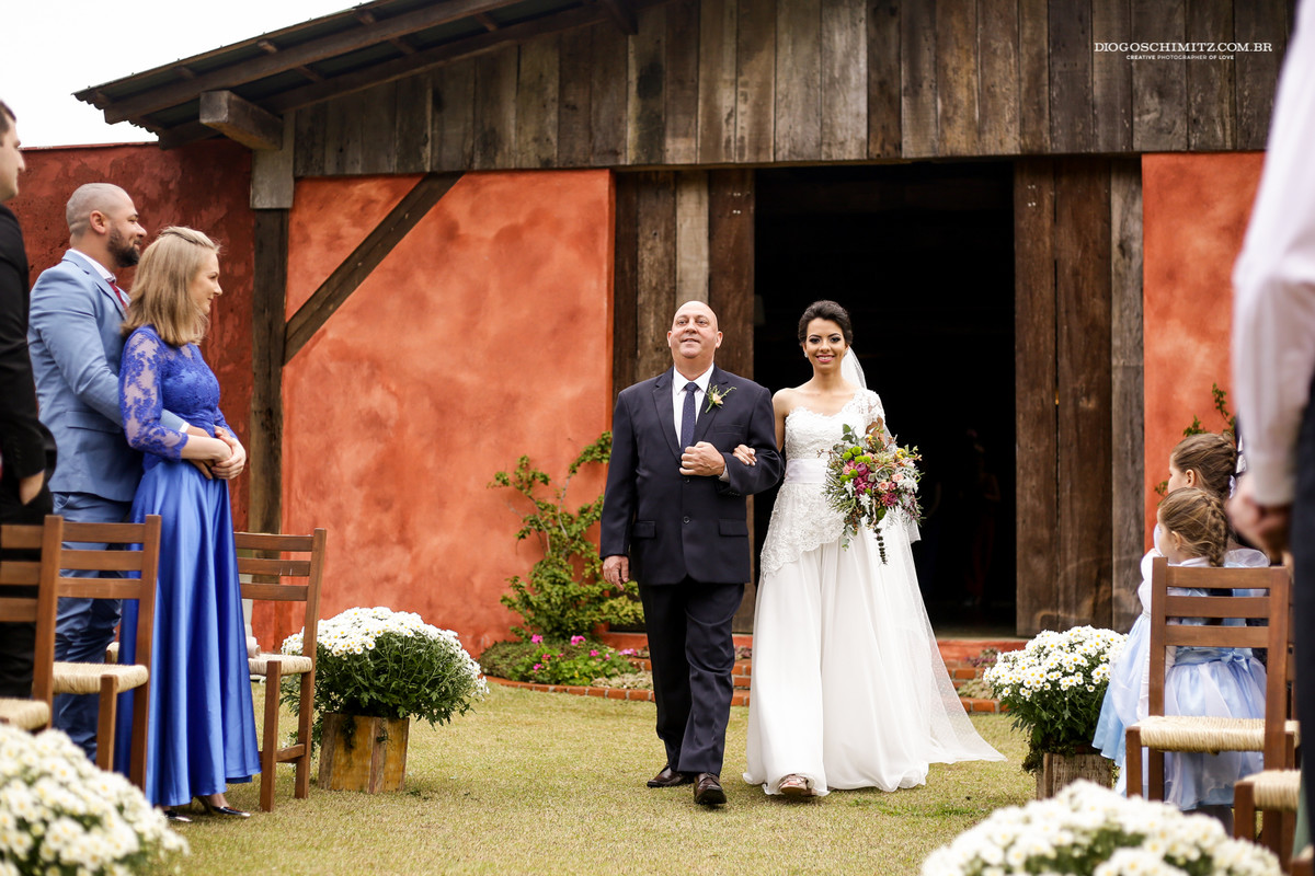 Noiva se emociona ao entrar com seu pai no casamento no campo.