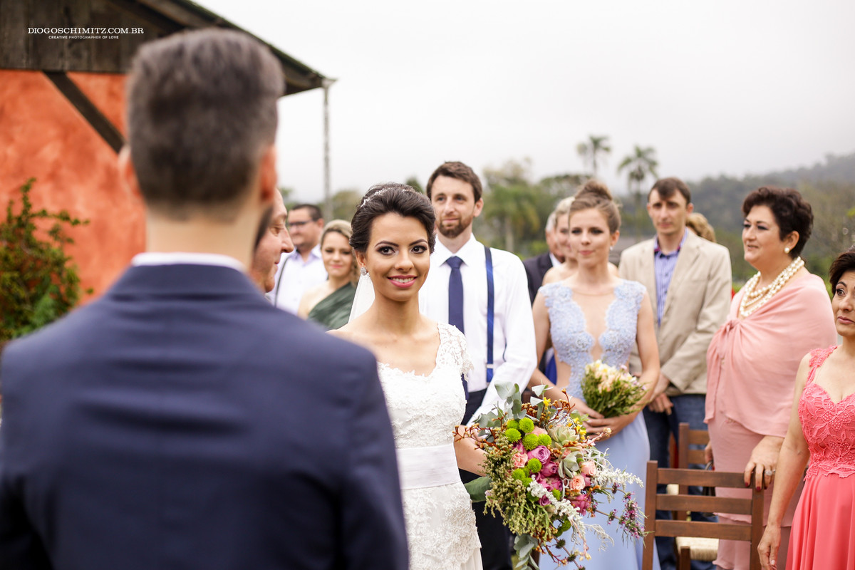 Noiva chora ao ver seu noivo esperando por ela no seu casamento no campo.