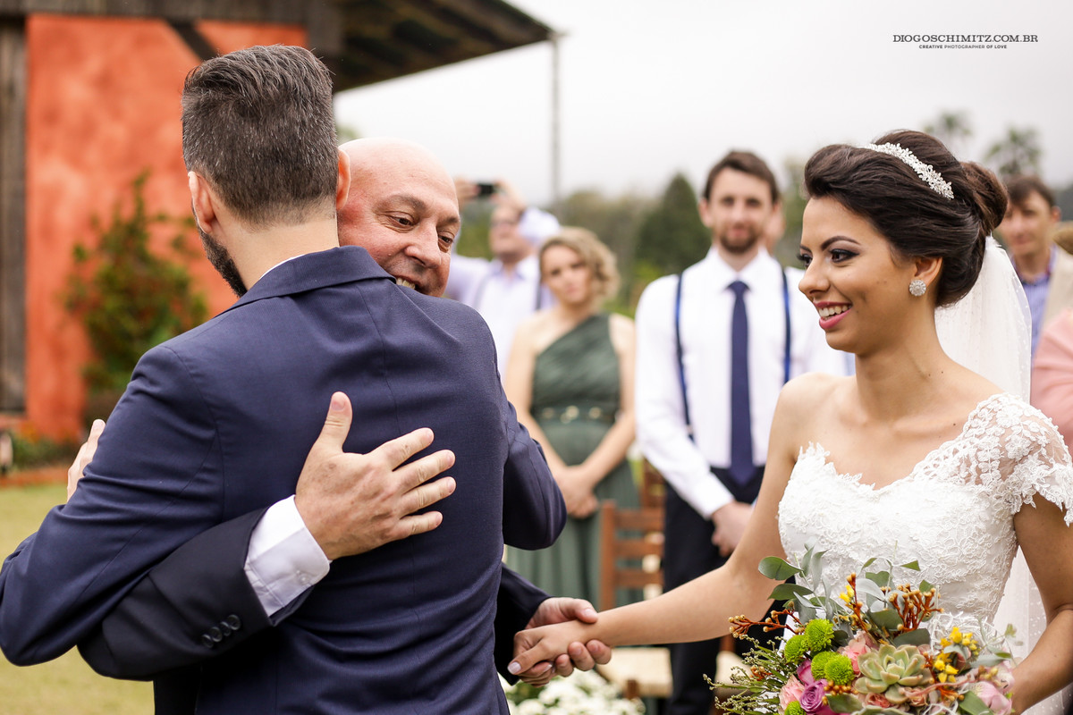 Pai da noiva abraça o noivo, e entrega a mão da noiva para o guiar ao futuro.