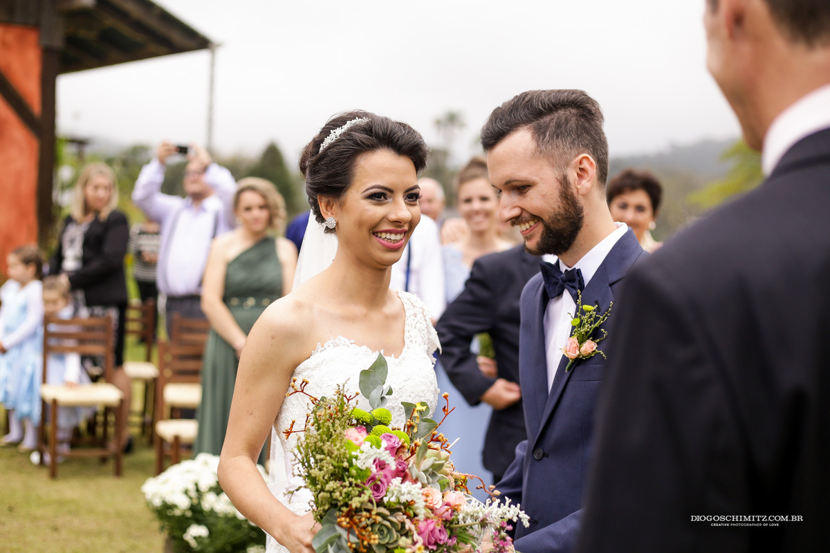 Noiva sorri ao pastor que vê o casal junto.