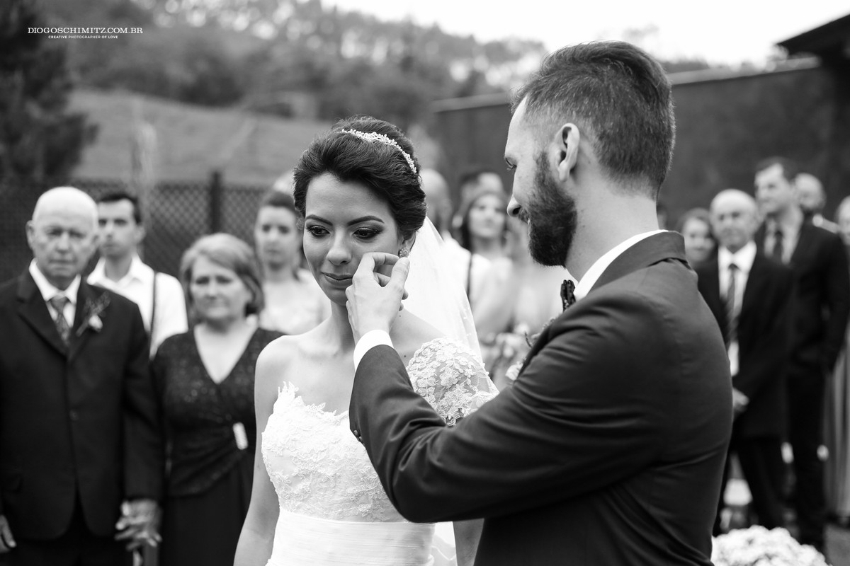 Momento em que noivo enxuga a lágrima da noiva.