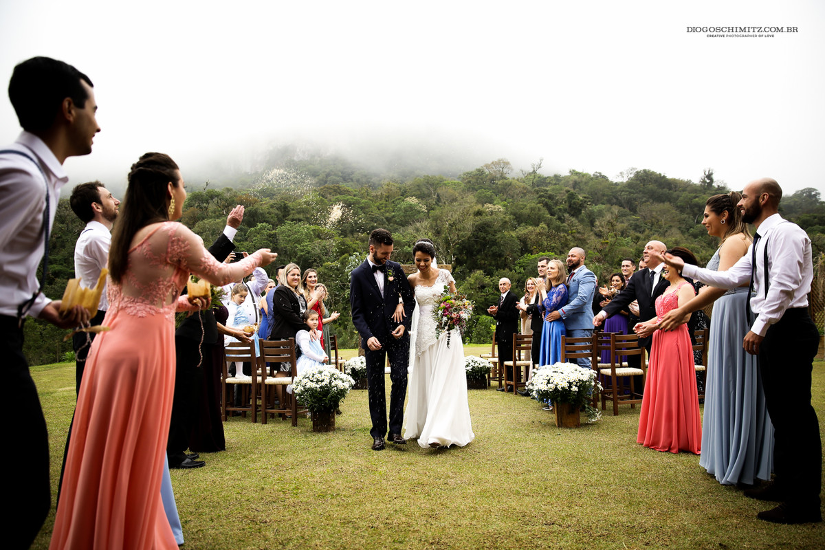 Saída dos noivos da cerimônia de casamento no campo.