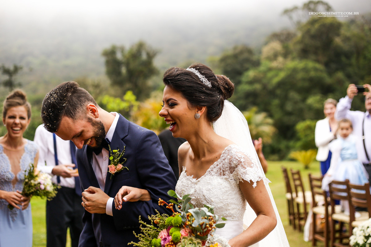 Noiva sorri na saída da cerimônia de casamento no campo.
