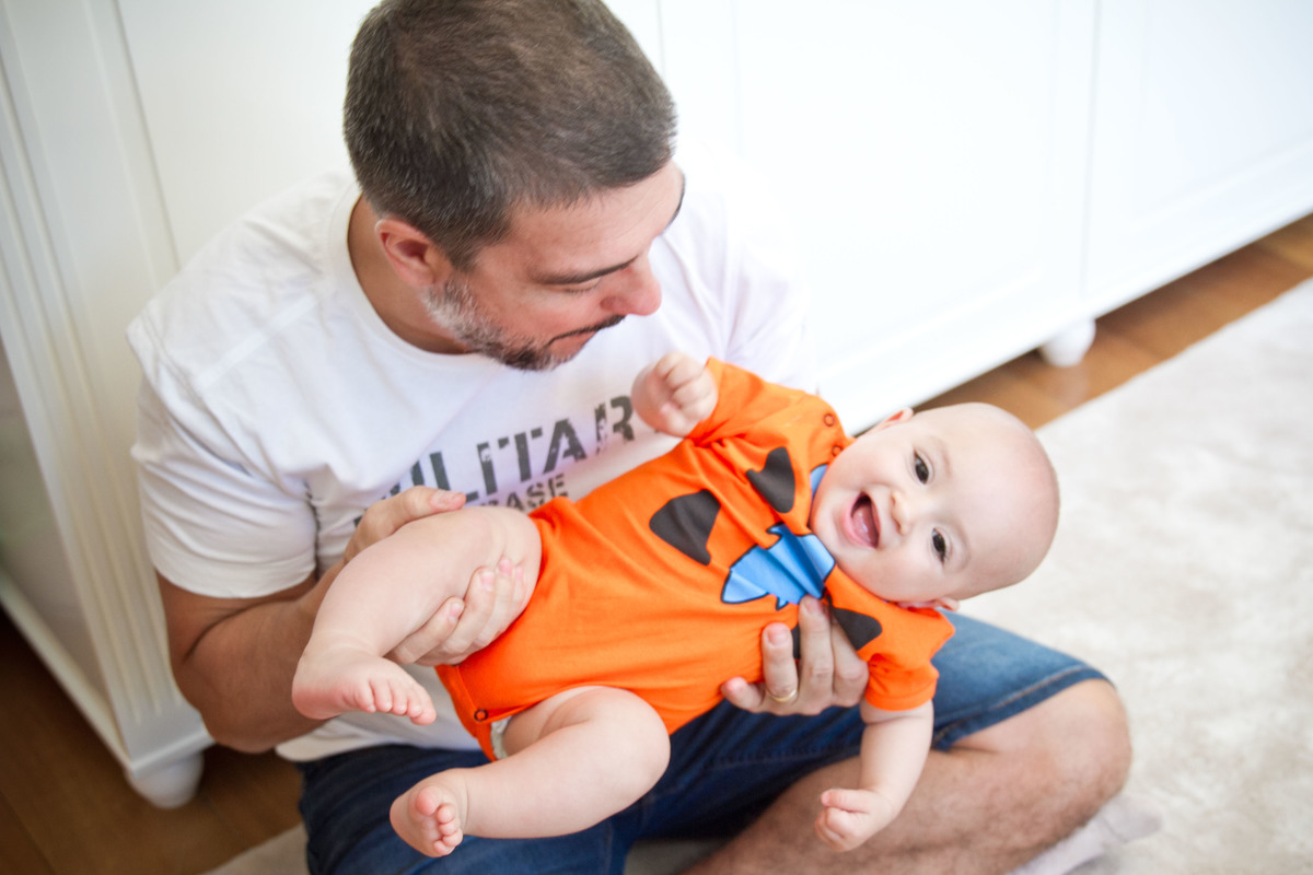 Bebe sorrindo no colo do pai fotografia