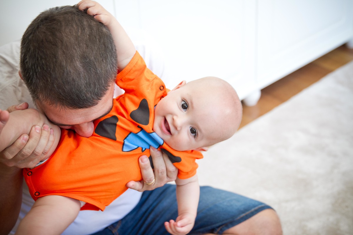 Fotografia de pai fazendo cocégas no filho