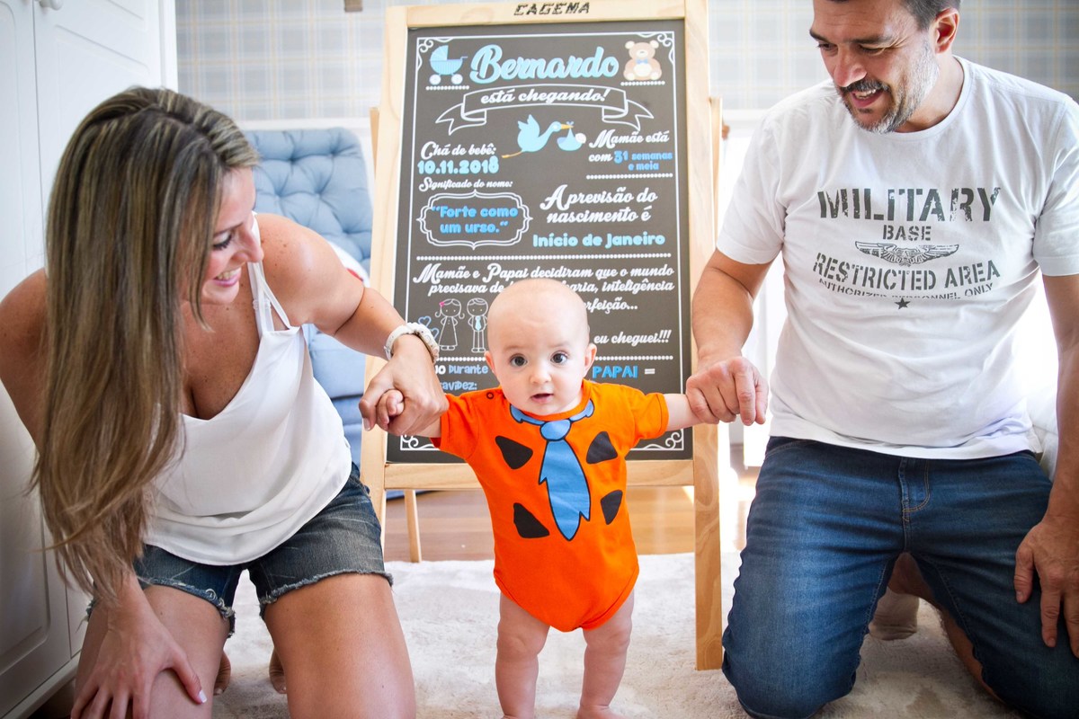 Fotografia de pais segurando as mãos do bebê