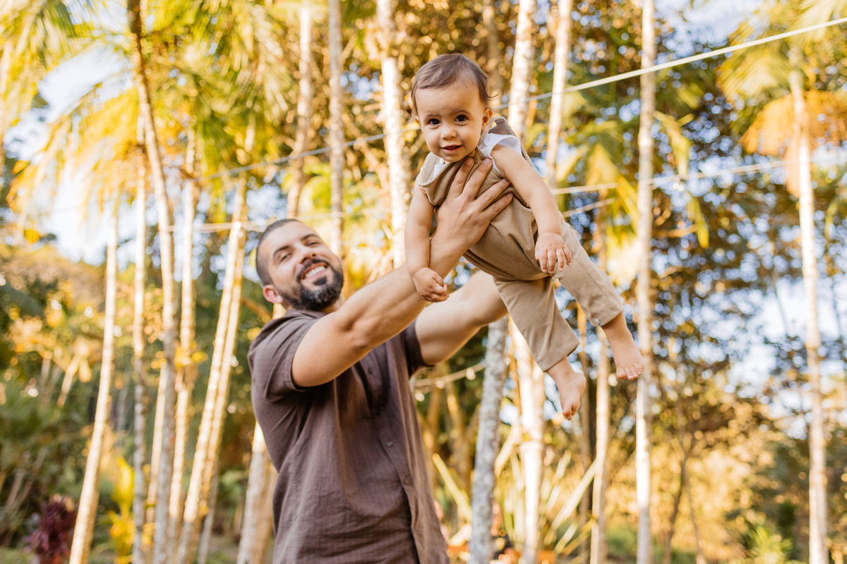 Fotografia documental de pai e filho brincando no jardim em aniversário infantil de 1 ano