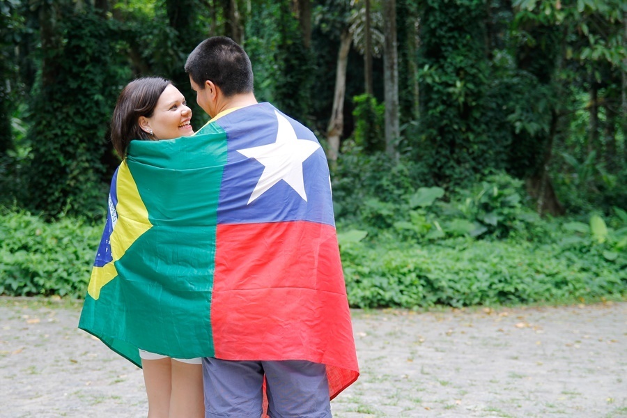Fotografia de casal abraçados no parque com as bandeiras do Brasil e do Chile - Rio de Janeiro- RJ