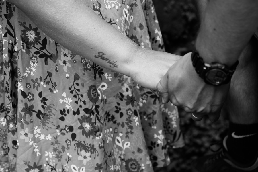 Fotografia em preto e branco de casal de mãos dadas mostrando a tatuagem  family no braço - Rio de Janeiro - RJ