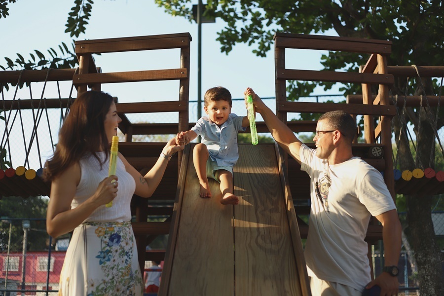 Fotografia dos pais com o filho  escorregando em um brinquedo - Rio de Janeiro - RJ