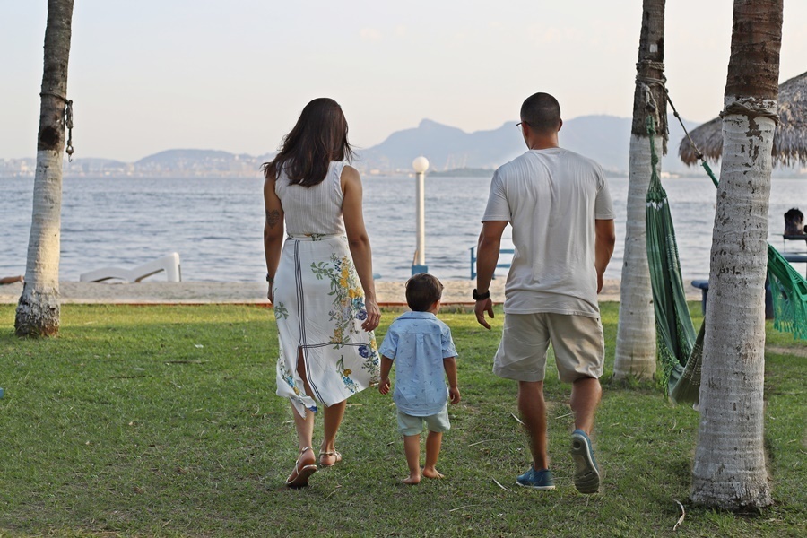 Fotografia dos pais com o filho caminhando em direção a uma praia- Rio de Janeiro - RJ