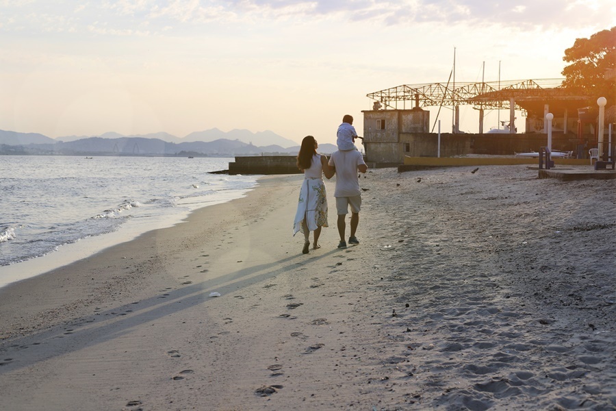 Fotografia dos pais com o filho caminhando em  uma praia- Rio de Janeiro - RJ