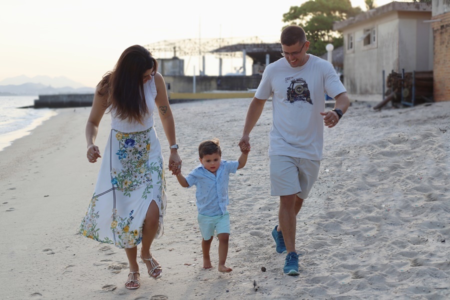 Fotografia dos pais com o filho caminhando em  uma praia- Rio de Janeiro - RJ