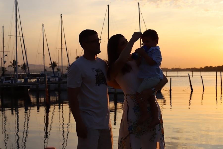 Fotografia dos pais com o filho no pôr do sol em um deck - Rio de Janeiro - RJ