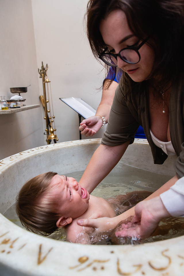madrinha mergulhando benjamin na agua para o batizado ortodoxo