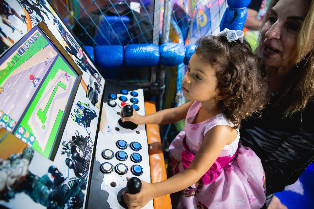 aniversariante com o vestido da patrulha canina jogando fliperama com a avó