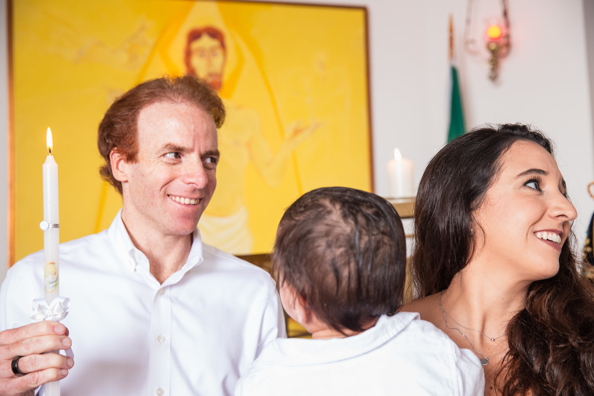 familia participando do batismo bençao do padre e vela do padrinho