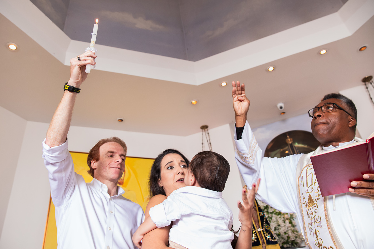 familia participando do batismo bençao do padre e vela do padrinho