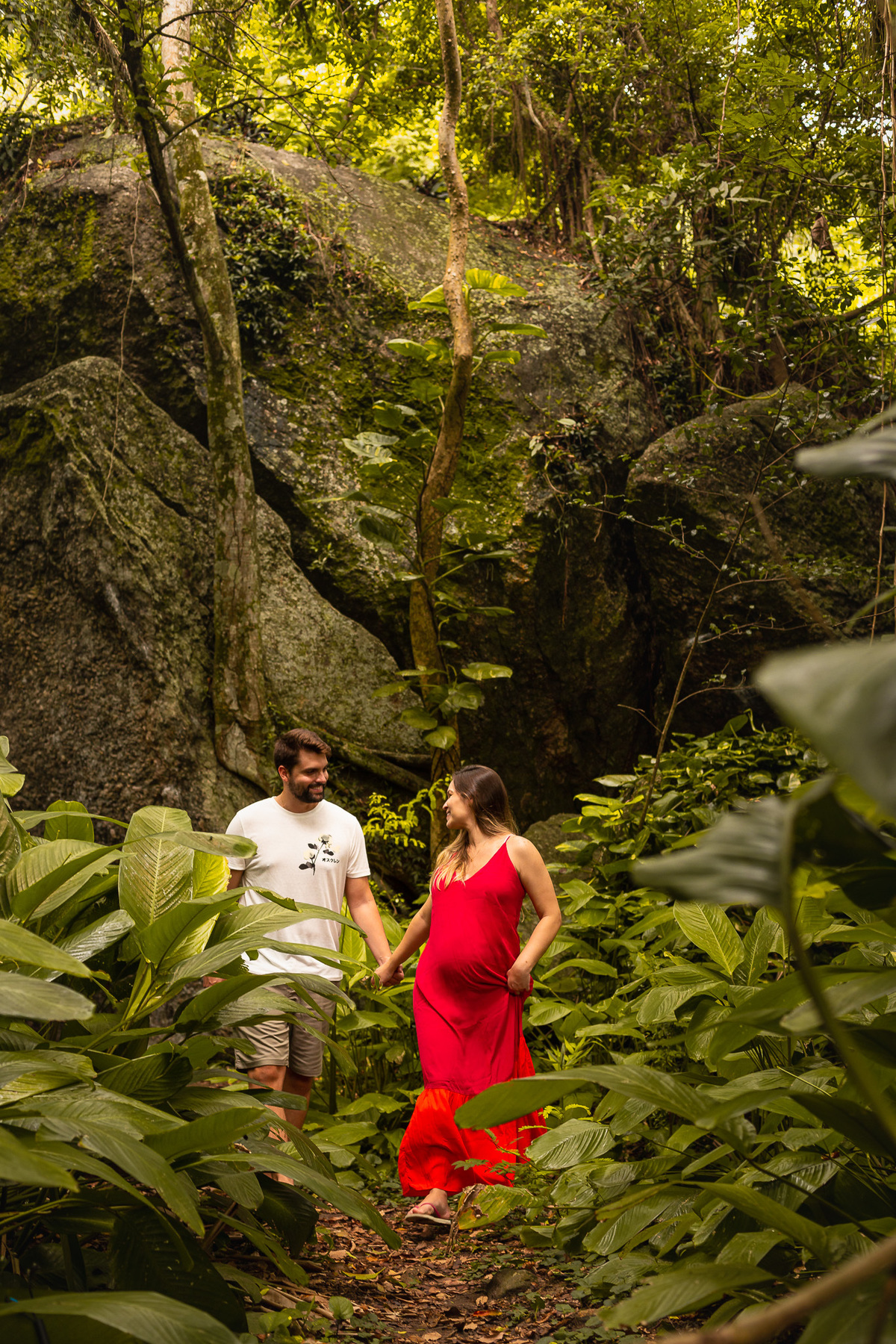casal gestante andando por um caminho de plantas verdes