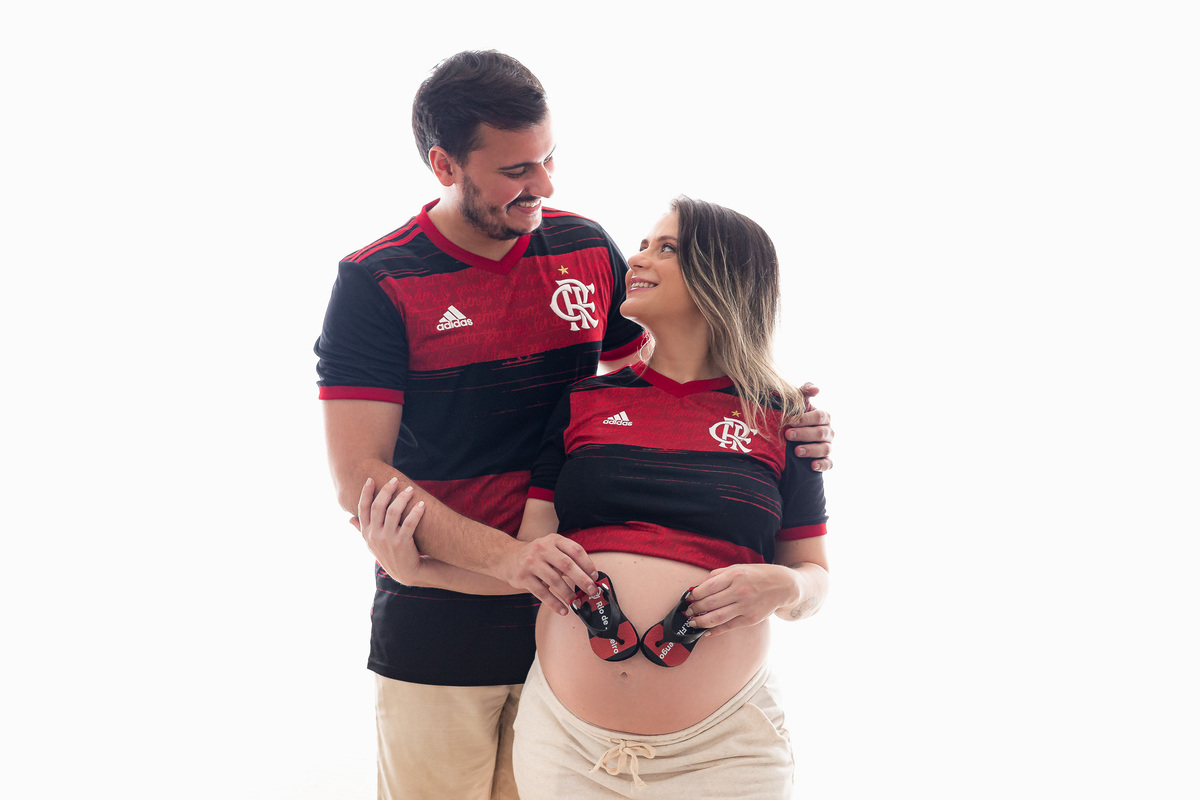 casal flamenguista com 30 semanas de gestação posando pra foto com um chinelinho do flamengo na barriga