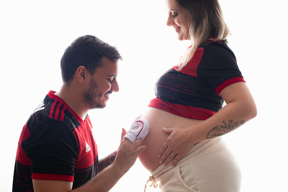 casal flamenguista com 30 semanas de gestação posando pra foto com um sapatinho do flamengo na barriga