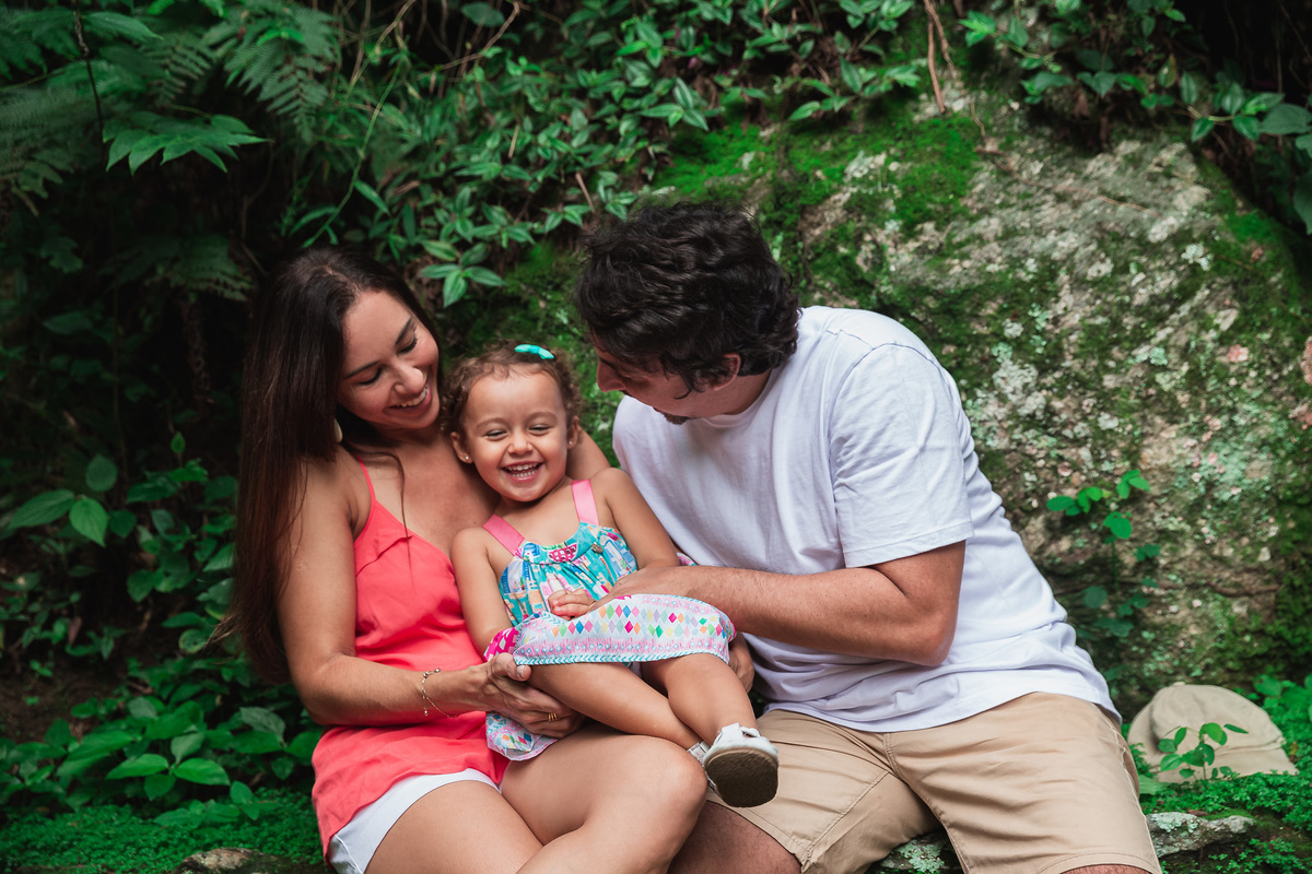 ensaio fotografico em familia no parque da catacumba mae e pai fazendo cosquinha na filha que sorri