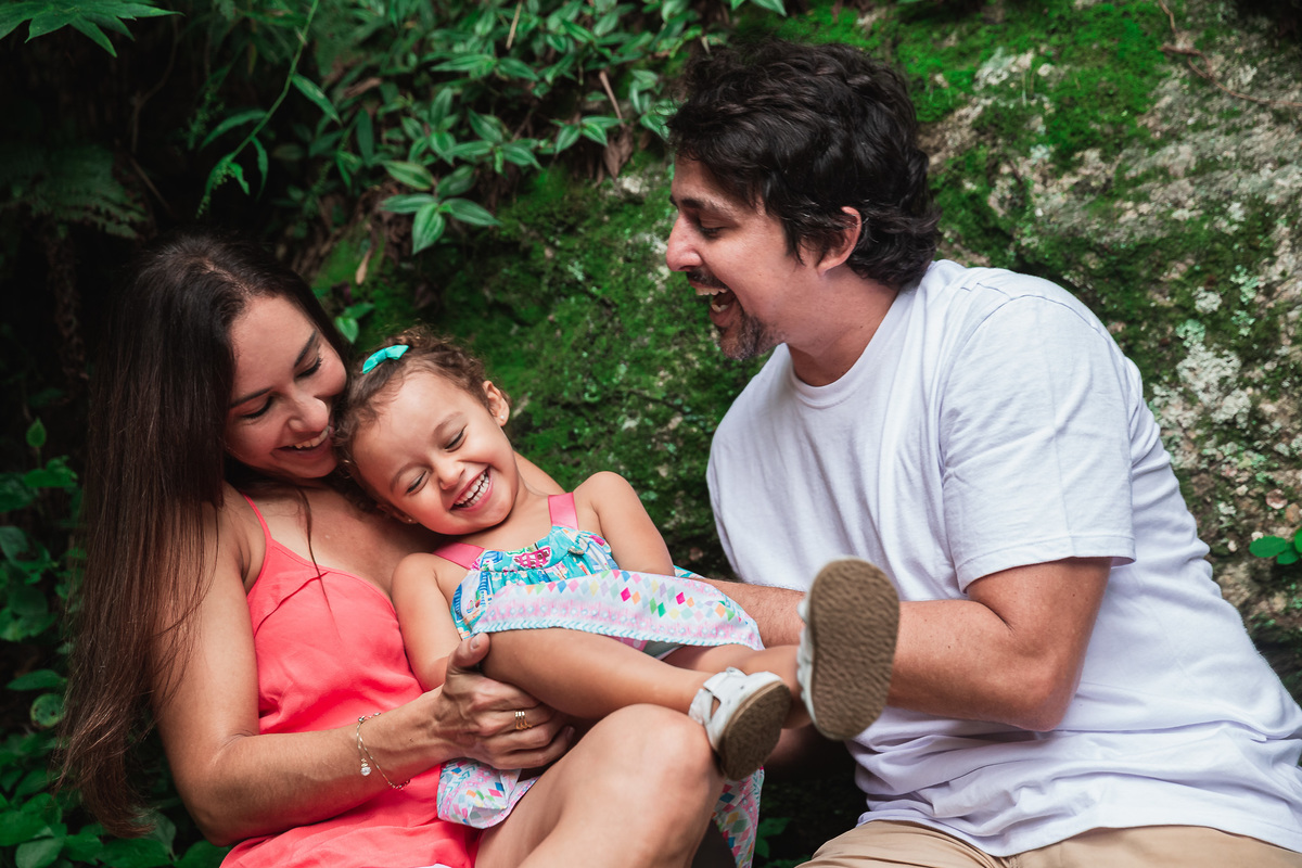 ensaio fotografico em familia no parque da catacumba mae e pai fazendo cosquinha na filha que sorri
