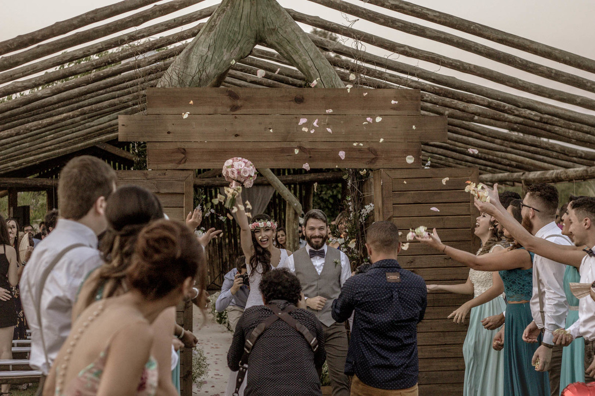 saída dos noivos no click do fotógrafo de casamento Bauru Thiago Figueredo noiva erguendo o buquê e noivo sorrindo