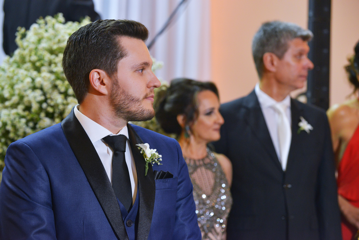 fotograia do noivo com seu pais ao fundo durante a entrada da noiva no casamento realizado no Buffet Espaço. Grenah