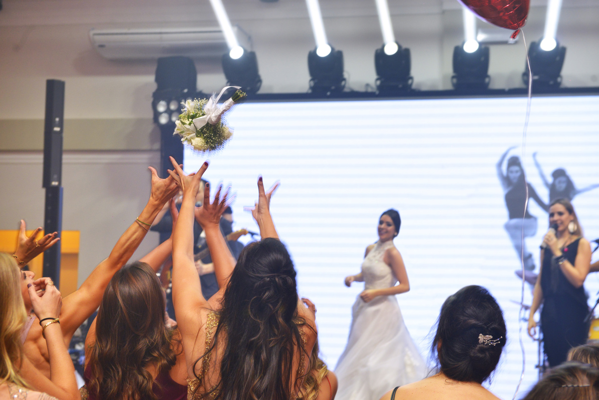 fotografia da noiva jogando o bouquet para as solteiras na recepção realizada no Buffet Espaço Grenah.