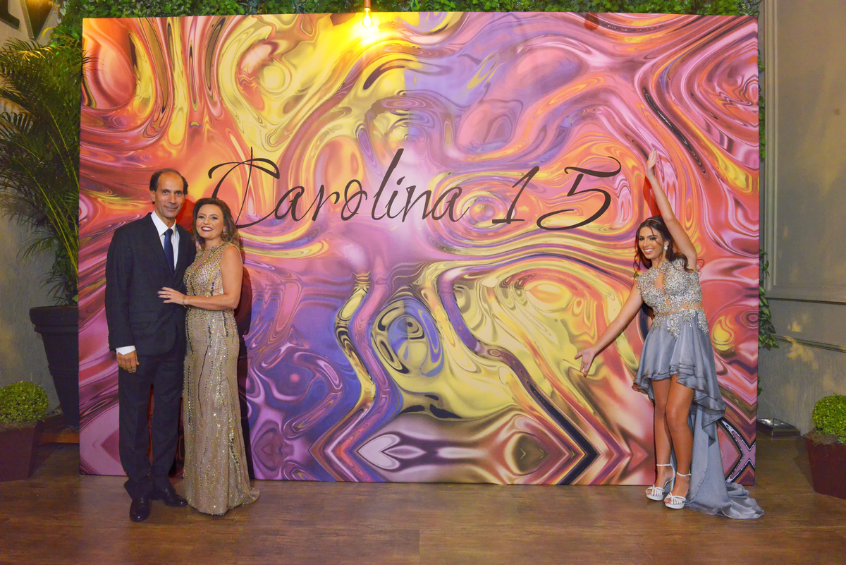 fotografia da debutante Carolina e dos pais em frente do painel instalado para os convidados fazerem suas selfies na Mansão Araci do buffet Mediterraneo