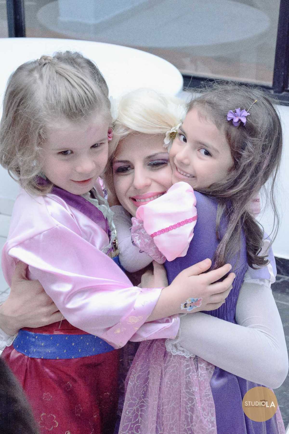 A aniversariante e uma amiguinha abraçam a personagem Rapunzel, em um momento de pura felicidade e encantamento. Fotografia de festa infantil registrada pelo Studio LA.
