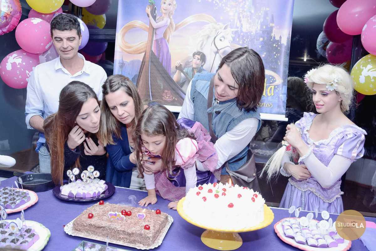 Criança soprando a vela do bolo em sua festa infantil com tema Rapunzel. Registro especial feito pelo Studio LA em salão de festas em São Paulo.