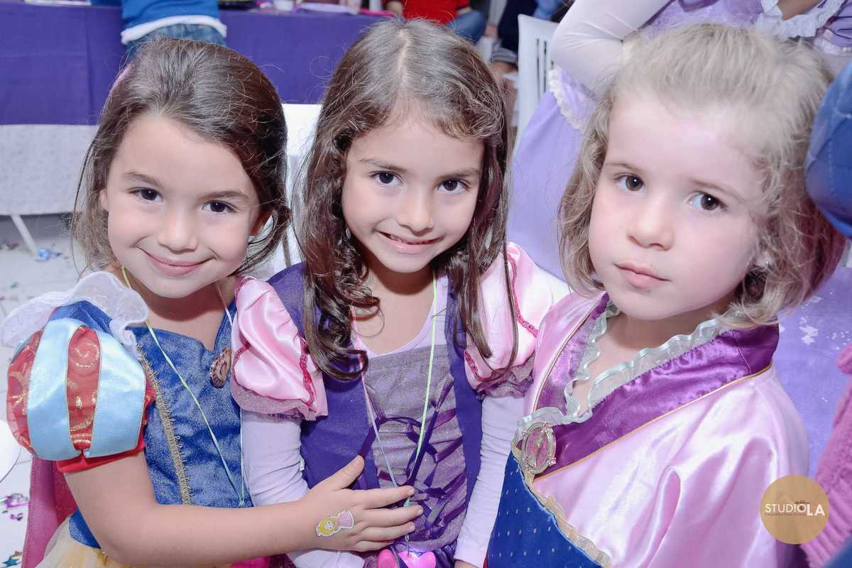 Amigas vestidas de princesas sorrindo juntas em festa infantil encantadora. Foto captada pelo Studio LA em São Paulo.