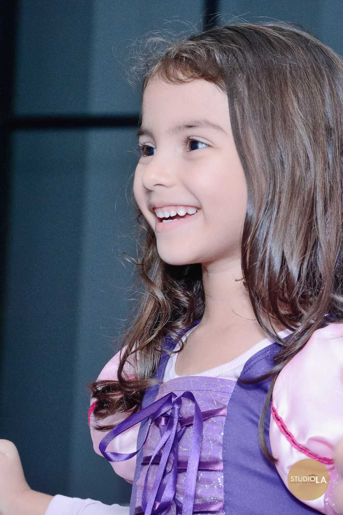 Retrato espontâneo da aniversariante sorrindo durante sua festa com tema Rapunzel. Fotografia profissional do Studio LA.
