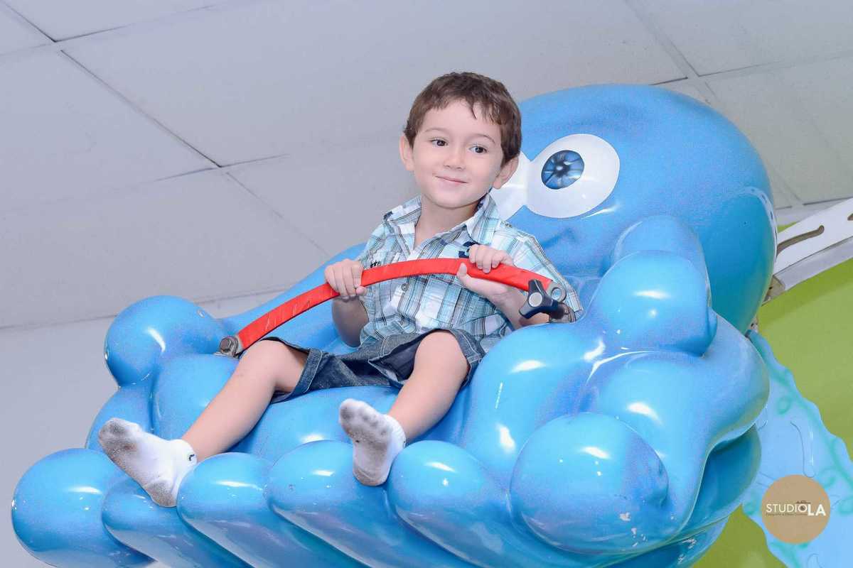 Registro divertido de criança rindo durante a brincadeira no air hockey em festa de aniversário infantil em SP. Foto captada pelo Studio LA.
