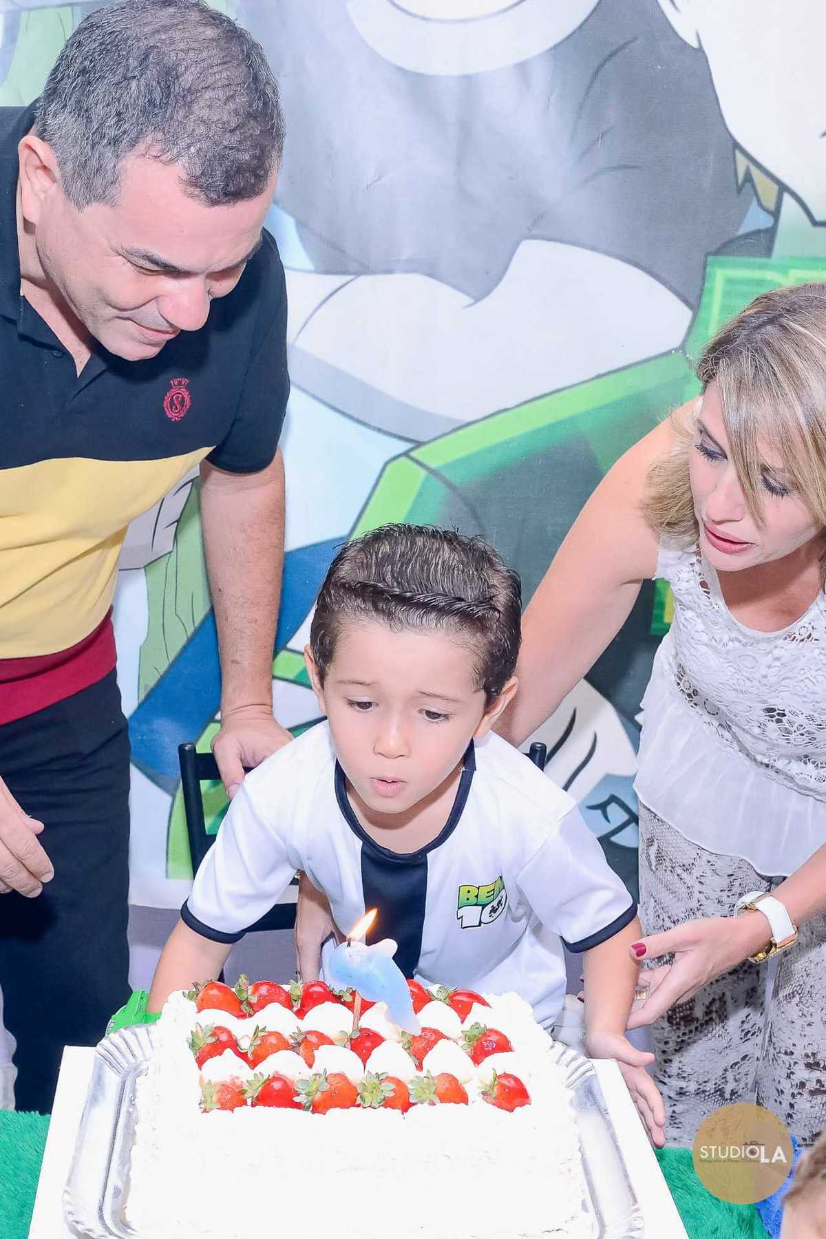 Hora especial de apagar a vela: aniversariante assopra o bolo ao lado dos pais, em um registro emocionante e cheio de alegria — fotografias de festa infantil feitas pelo Studio LA.