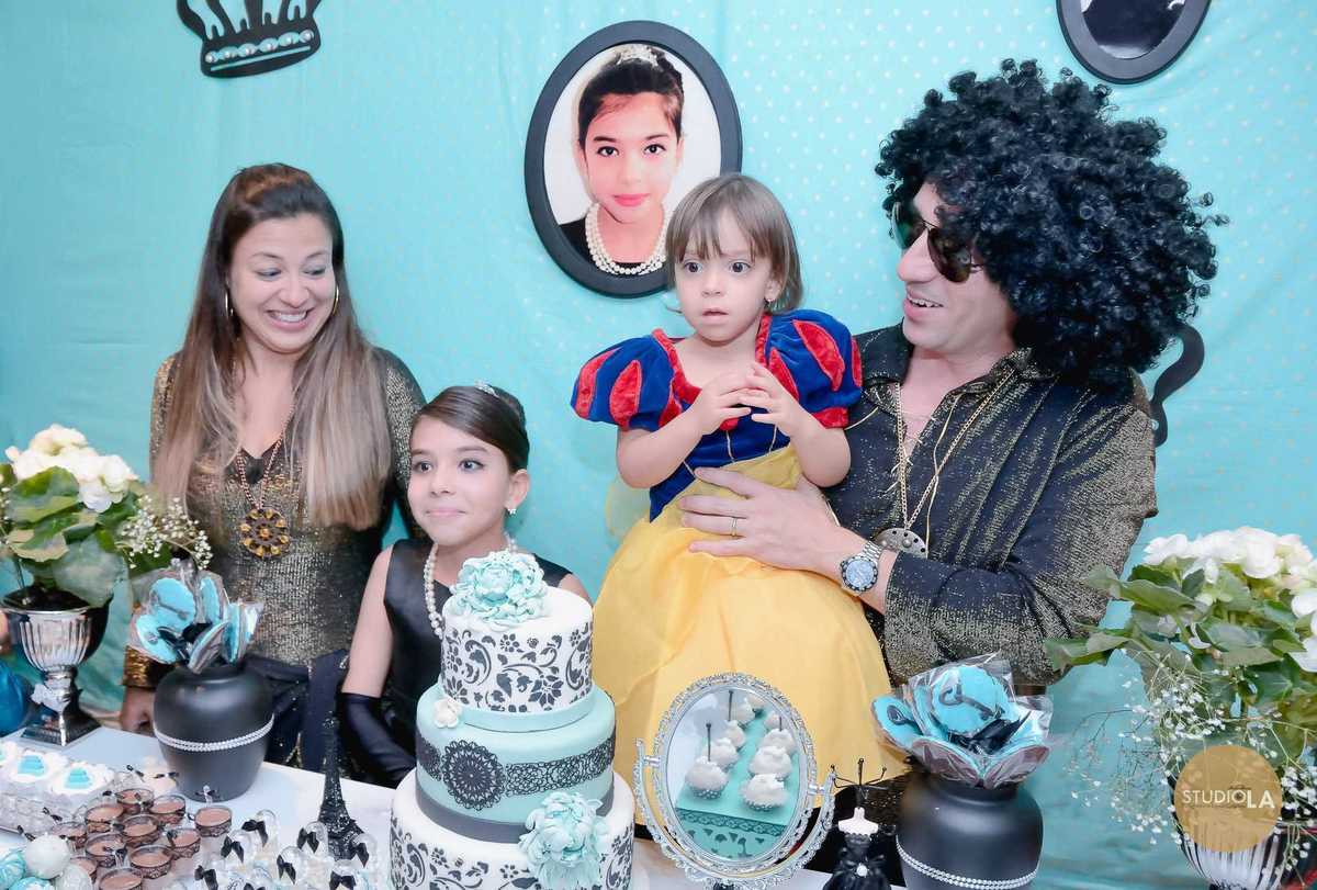 Fotografia de festa infantil em salão de festas em São Paulo, captada pelo Studio LA, mostrando a família reunida na mesa do bolo decorado com muito estilo, celebrando com alegria.