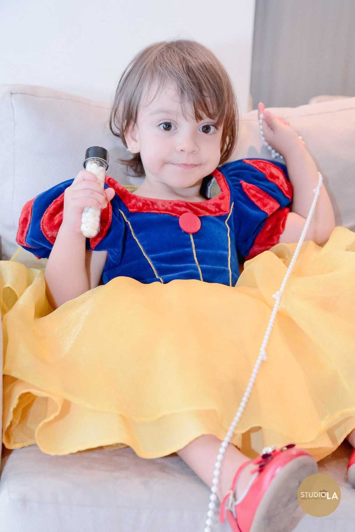 Registro encantador de aniversário infantil em São Paulo, fotografado pelo Studio LA, com a pequena convidada vestida de Branca de Neve em um momento espontâneo e cheio de doçura.