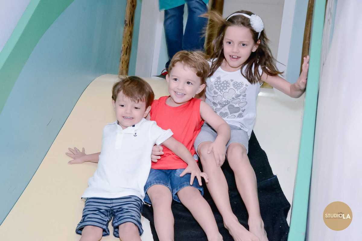 Foto alegre de crianças descendo juntas no escorregador durante a festa infantil no Buffet Feliz da Vida em São Paulo — registros Studio LA.