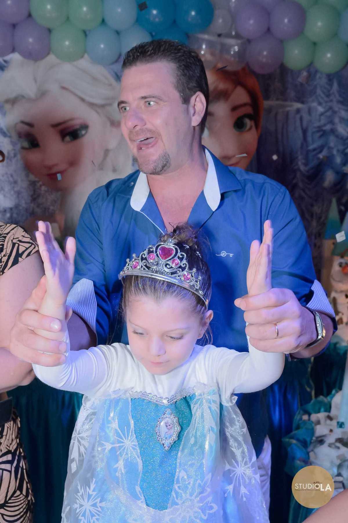 Hora do parabéns com aniversariante soprando a vela em seu bolo temático Frozen, em festa infantil no buffet em São Paulo. Foto emocionante feita pelo Studio LA.