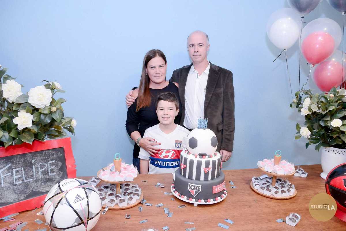 Foto de aniversário infantil com o aniversariante assoprando as velas do bolo em formato de bola de futebol. Registro cheio de emoção realizado pelo Studio LA Fotografia Infantil em SP.
