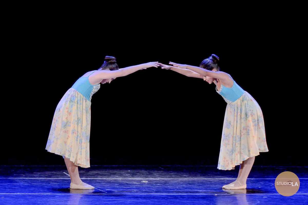 4.	Espetáculo de dança infantil em São Paulo – Fotografia de duas bailarinas em apresentação teatral, captada pelo Studio LA, transmitindo harmonia e sincronia na coreografia.