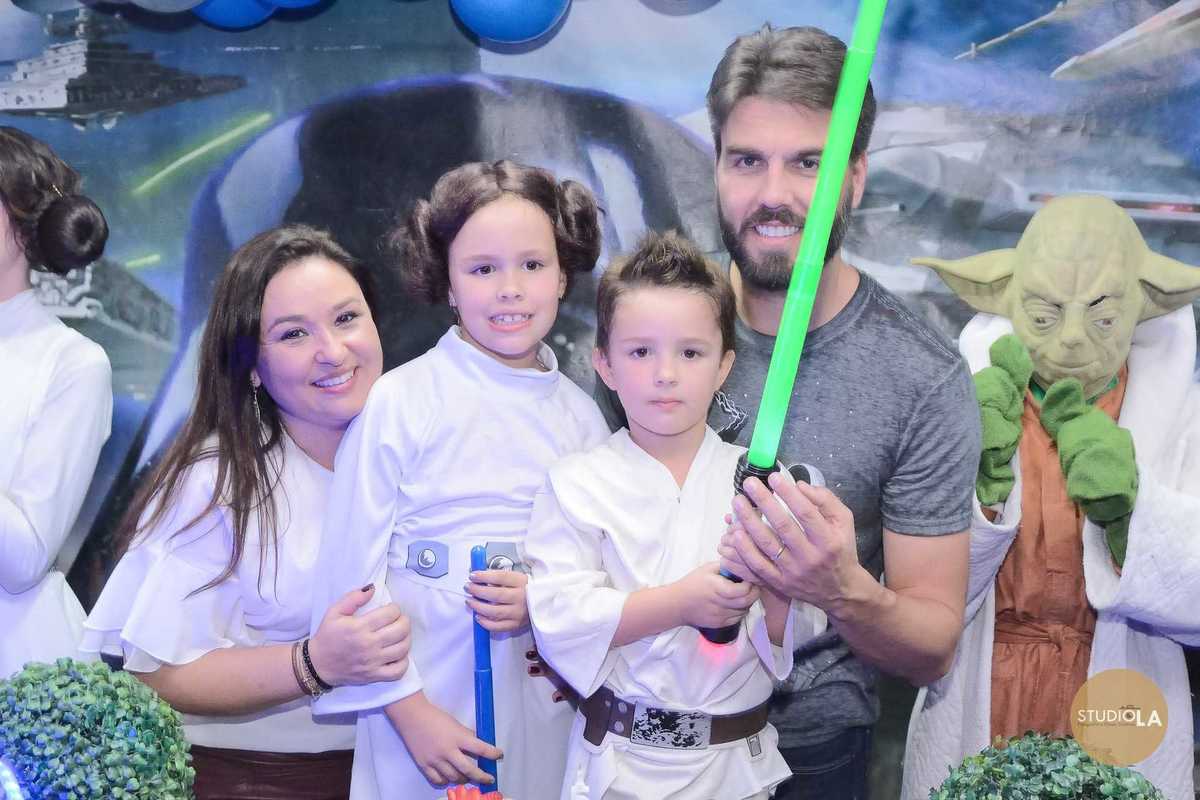 Família comemorando aniversário infantil com filhos fantasiados de Star Wars em frente à decoração temática — Fotografia de festa infantil feita pelo Studio LA.