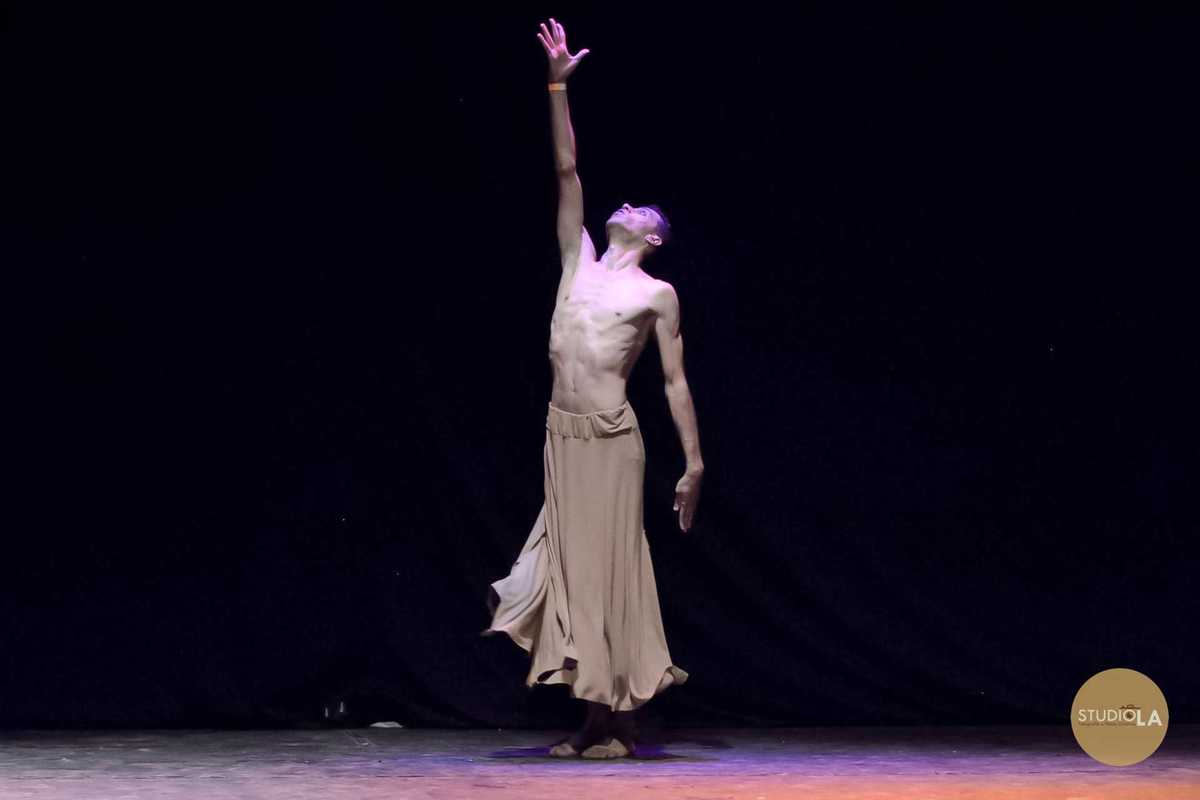 Fotografia de apresentação de balé contemporâneo, com bailarino em figurino branco realizando movimento de alta performance no palco. Registro artístico do Studio LA.
